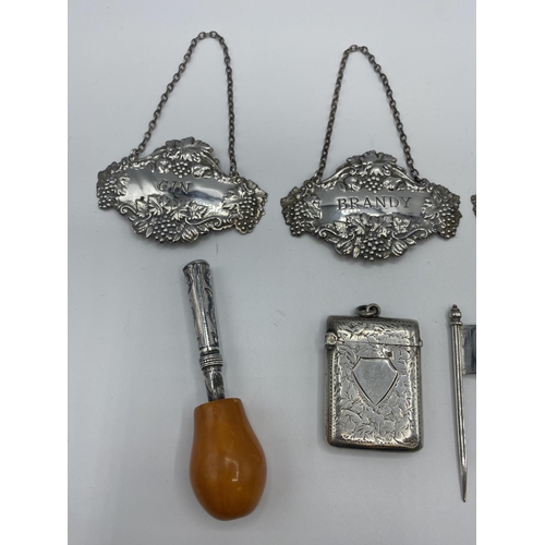 143 - A collection of sterling silver items, to include decanter labels, cheese flags, vesta, and a white ... 