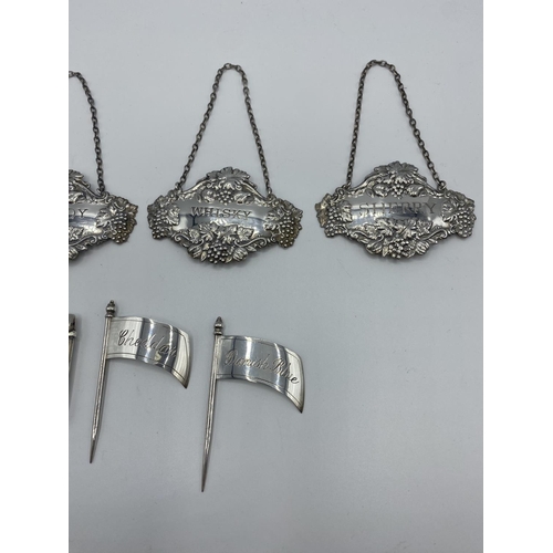 143 - A collection of sterling silver items, to include decanter labels, cheese flags, vesta, and a white ... 