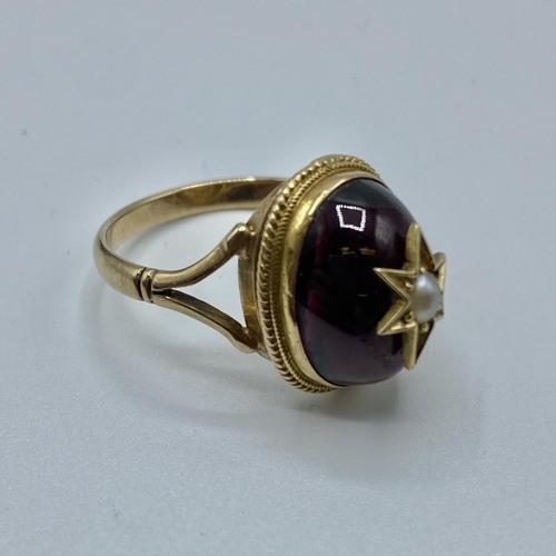 26 - A Victorian unmarked yellow metal garnet and seed pearl dress ring, oval cabochon garnet with star s... 