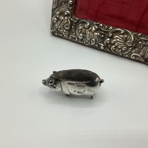 19 - A Sterling silver pin cushion in the form of a pig, together with an unmarked white metal photo fram... 