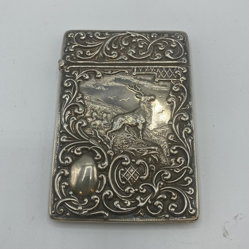 99 - Two sterling silver card cases, one with a stag in a landscape, vacant cartouche, scrolling surround... 