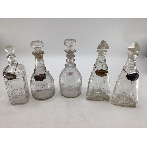 230 - A collection of C19th/C20th glass decanters, a triple ring necked example, some with white metal lab... 