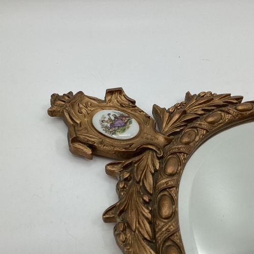 250 - A gilt framed oval mirror, topped by inset ceramic oval panel, bevelled plate, 43-78cm