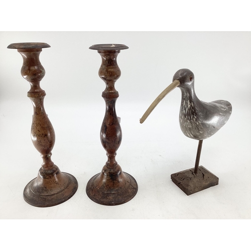 369 - A pair of Indian metal candlesticks together with a carved model of a bird on stand, (Sticks 35cmh)