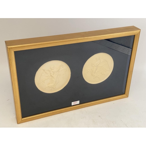 523 - A gilt framed and glazed mounted circular plaster reliefs of winged classical figures