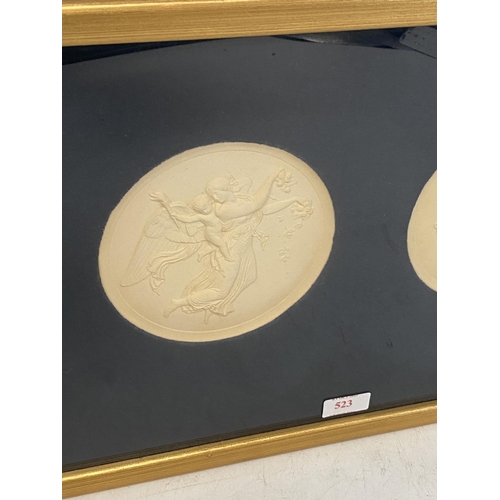 523 - A gilt framed and glazed mounted circular plaster reliefs of winged classical figures