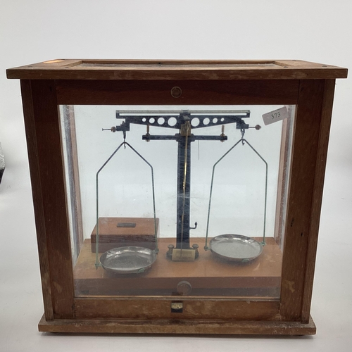 1033 - An early 20th century pair of chemists scales with boxed associated weights in an oak and glass case... 