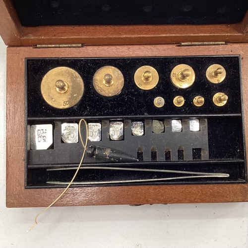 1033 - An early 20th century pair of chemists scales with boxed associated weights in an oak and glass case... 