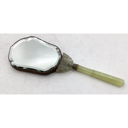 210 - A dressing table hand mirror, decorated to back with carved jade style flowers and fauna