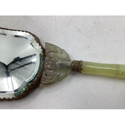 210 - A dressing table hand mirror, decorated to back with carved jade style flowers and fauna