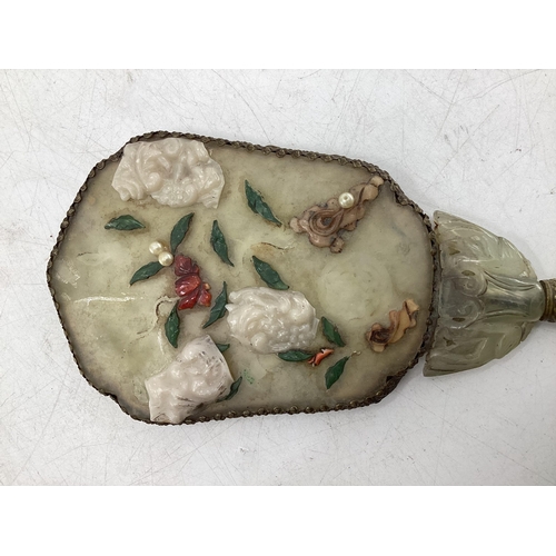 210 - A dressing table hand mirror, decorated to back with carved jade style flowers and fauna