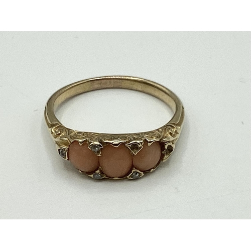 11 - An unmarked yellow metal pink coral and diamond ring. Three oval coral cabochons with rose cut diamo... 