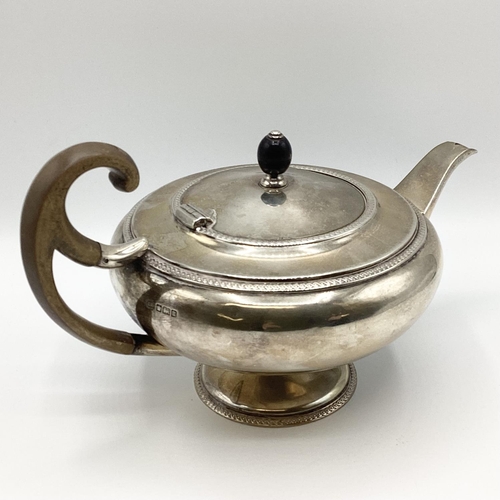 21 - A sterling silver tea pot of bulbous form with fruit wood handle by John Roberts, Sheffield. 1912. 5... 