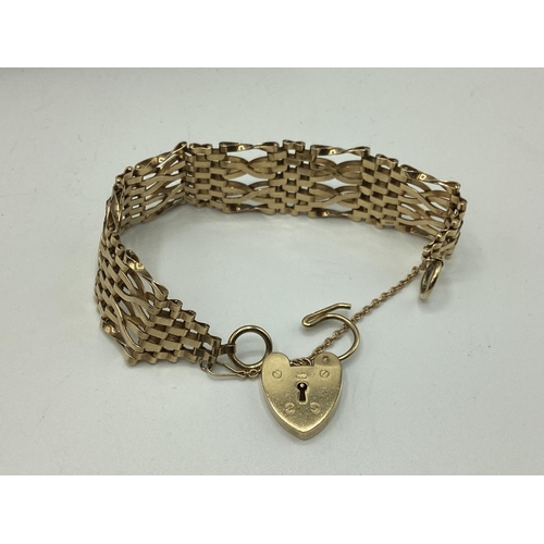 6 - A 9ct gold flat gate link bracelet with 9ct gold heart locket. 25.80g.