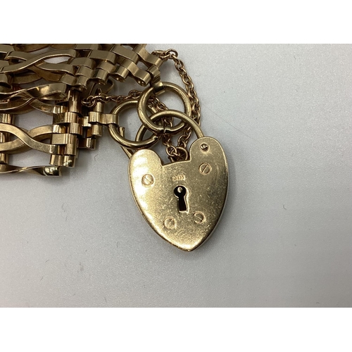 6 - A 9ct gold flat gate link bracelet with 9ct gold heart locket. 25.80g.