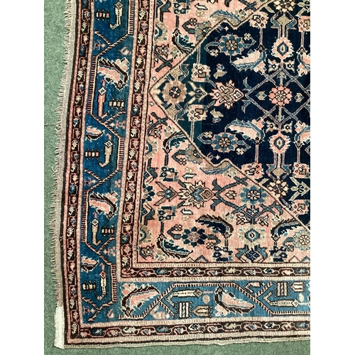 640 - A Persian style rug, with blue border, and central medallion of dark blue ground with pink/cream and... 