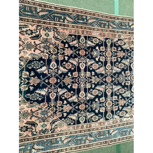 640 - A Persian style rug, with blue border, and central medallion of dark blue ground with pink/cream and... 