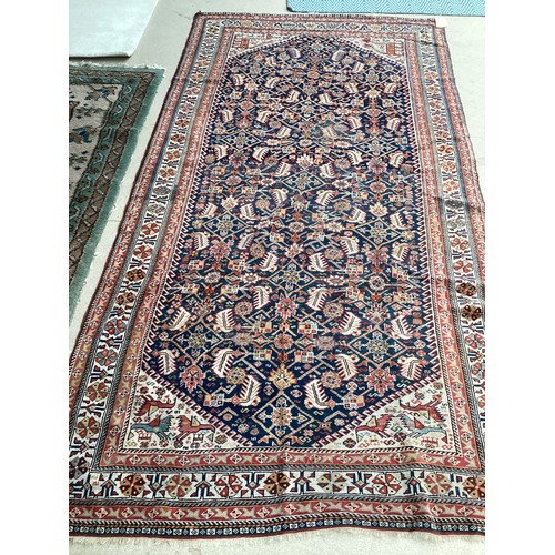 637 - A Kurdish style wool rug with stylized central pattern on blue and red ground, 142cm x 270cm