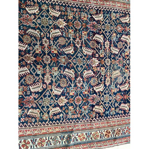 637 - A Kurdish style wool rug with stylized central pattern on blue and red ground, 142cm x 270cm