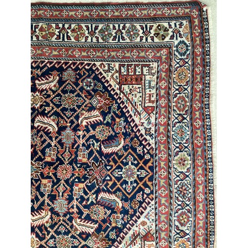 637 - A Kurdish style wool rug with stylized central pattern on blue and red ground, 142cm x 270cm