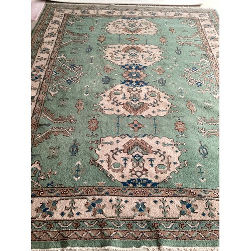 599 - A Turkish style wool rug, central cream medallion on green ground with floral and geometric borders.... 