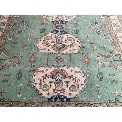 599 - A Turkish style wool rug, central cream medallion on green ground with floral and geometric borders.... 