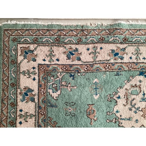 599 - A Turkish style wool rug, central cream medallion on green ground with floral and geometric borders.... 