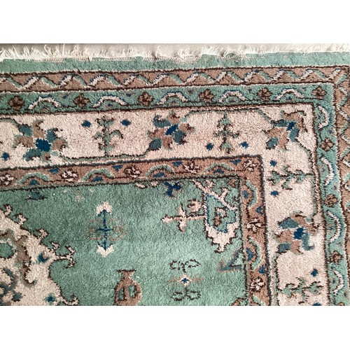 599 - A Turkish style wool rug, central cream medallion on green ground with floral and geometric borders.... 