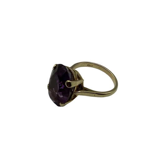 11 - A 9ct gold and amethyst dress ring. Central  oval free cut amethyst, Approx 17mm x 12mm in a four cl... 