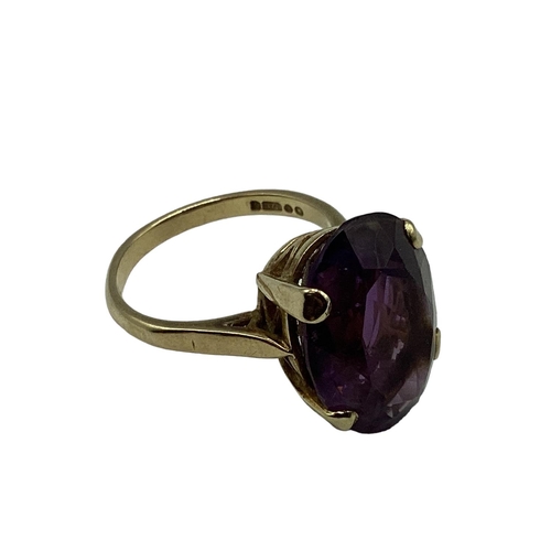 11 - A 9ct gold and amethyst dress ring. Central  oval free cut amethyst, Approx 17mm x 12mm in a four cl... 