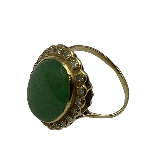 8 - An unmarked yellow metal jade and diamond dress ring, central oval jade cabochon with a surround of ... 