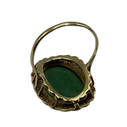 8 - An unmarked yellow metal jade and diamond dress ring, central oval jade cabochon with a surround of ... 