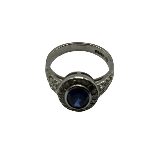 7 - A 18ct white gold sapphire and diamond ring, central oval free cut sapphire in a rub over setting wi... 