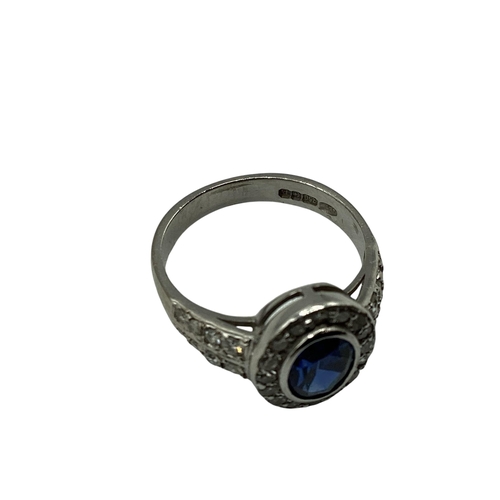 7 - A 18ct white gold sapphire and diamond ring, central oval free cut sapphire in a rub over setting wi... 