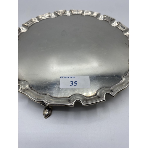 35 - A sterling silver circular card tray with cast border on three feet. 21cm(d) by Edward Barnard & Son... 