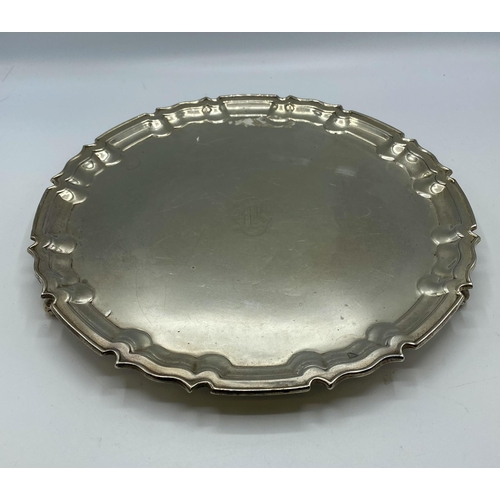 47 - A sterling silver circular tray on three scroll feet by William Hutton and Sons Ltd, Sheffield 1922.... 