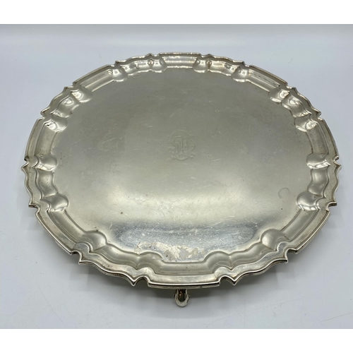 47 - A sterling silver circular tray on three scroll feet by William Hutton and Sons Ltd, Sheffield 1922.... 