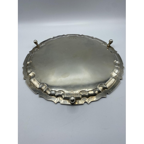 47 - A sterling silver circular tray on three scroll feet by William Hutton and Sons Ltd, Sheffield 1922.... 