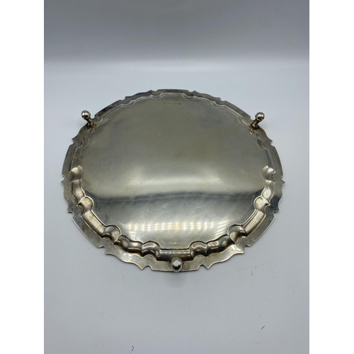 47 - A sterling silver circular tray on three scroll feet by William Hutton and Sons Ltd, Sheffield 1922.... 