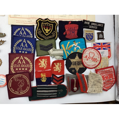 209 - A collection of Militaria to include cap badges , cloth insignia etc,