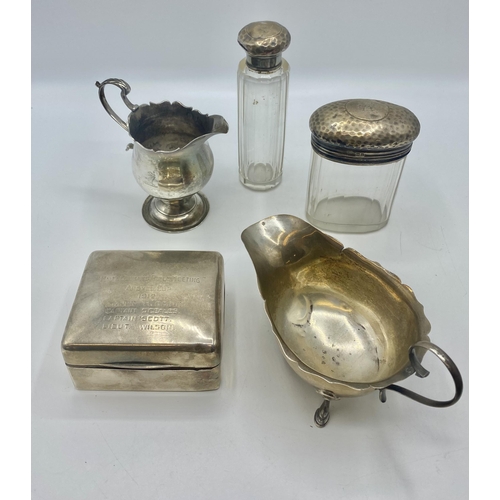 26 - A collection of sterling silver items to include a sauce boat, cream jug, cedar lined cigarette box ... 