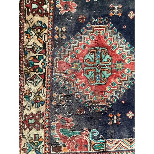 506 - Small blue rug with beige borders and three centred medallion 109 cm x 156 cm, some wear and damage ... 