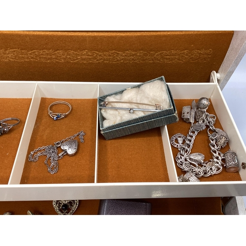 57 - A collection of sterling silver, white metal and costume jewellery in a cream jewellery casket.