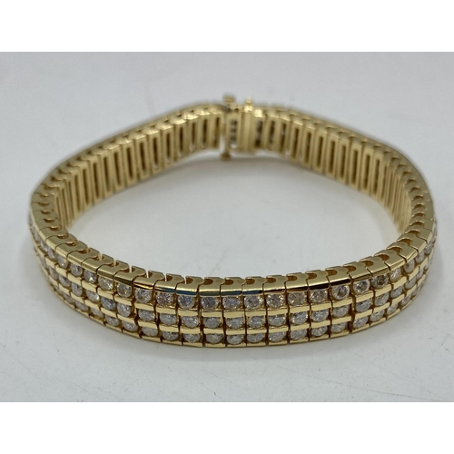 75 - An unmarked yellow metal diamond belt bracelet. Three uniform lines of 65 brilliant cut diamonds. 20... 