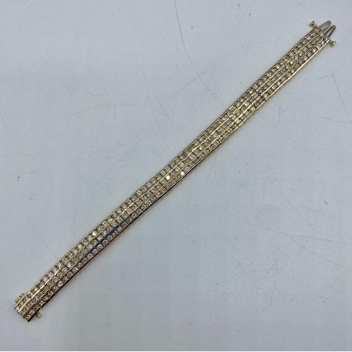 75 - An unmarked yellow metal diamond belt bracelet. Three uniform lines of 65 brilliant cut diamonds. 20... 
