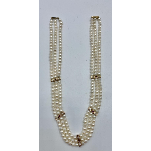 80 - A triple strand of uniform cultured pearls with diamond and ruby set yellow metal separators and unm... 