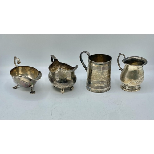 145 - A collection of sterling silver items to include a mug , cream jug, sauce boat etc. Various dates an... 