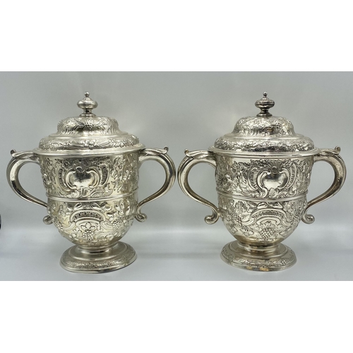 1 - A pair of sterling silver lidded trophy cups with repousse decoration one by James Dixon and Sons Sh... 