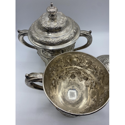 1 - A pair of sterling silver lidded trophy cups with repousse decoration one by James Dixon and Sons Sh... 