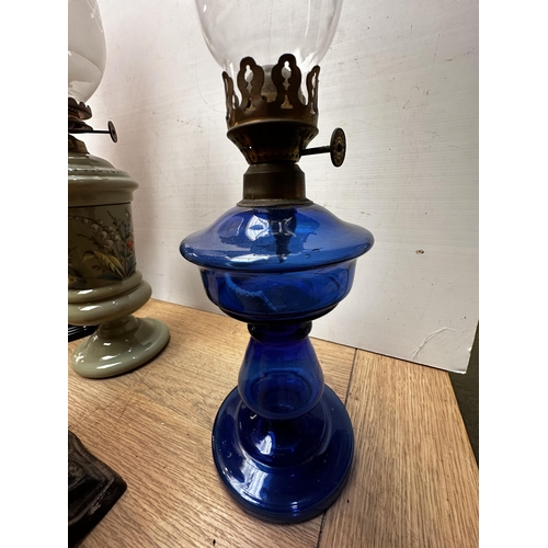 292 - A collection of five oil lamps one with opaline reservoir and cast metal base, the largest with etch... 